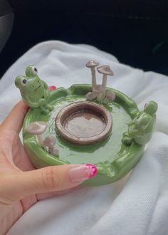 a person holding a green frog ring dish with mushrooms and toad rings on the top