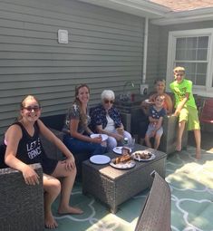 a group of people sitting on top of wicker couches in front of a house