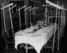 an old black and white photo of a long table with candles, flowers and scissors on it