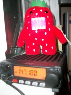 a red stuffed animal sitting on top of a radio