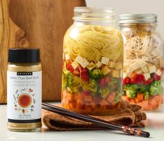 three jars filled with different types of food next to chopsticks and a wooden cutting board