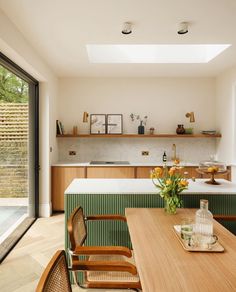 an open kitchen and dining room area with wooden table, chairs, counter top and sliding glass doors