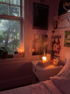 a bedroom with a window, candles and pictures on the wall