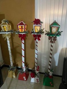 three christmas decorations are on display in front of a wall with a light up house and candy canes