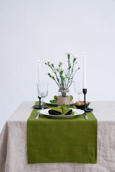 the table is set with candles and flowers in vases on it, along with two place settings