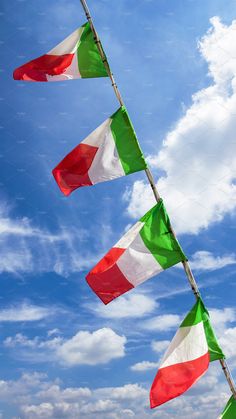 three italian flags flying in the wind on a sunny day with blue sky and clouds