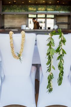 two white chairs with flowers and greenery tied to them, sitting in front of a bar