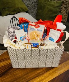 a basket filled with food sitting on top of a wooden table next to a pillow