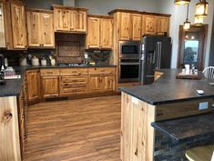 a large kitchen with wooden cabinets and black counter tops, along with an island in the middle