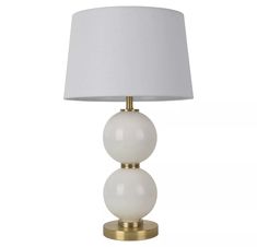 a white lamp on a gold base with a white shade over the lampshade