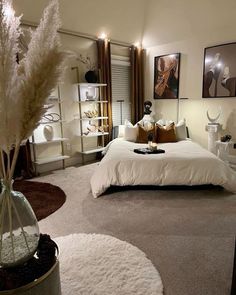 a bedroom with a large bed and pictures on the wall above it, along with white rugs