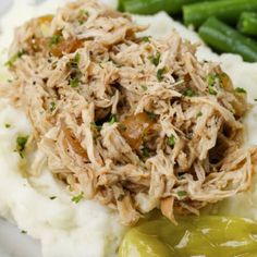 a close up of food on a plate with mashed potatoes and green beans in the background