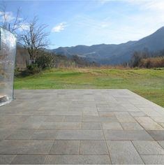 an empty patio in the middle of a grassy area with mountains in the back ground