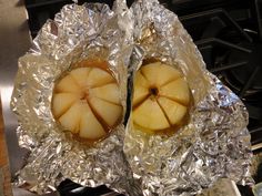 two pieces of fruit sitting on top of aluminum foil covered in tinfoil next to an oven