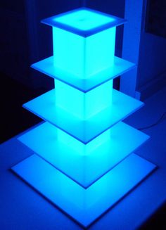 three illuminated cubes are stacked on top of each other in the middle of a room