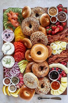 an assortment of doughnuts, fruit and dips on a platter with bacon