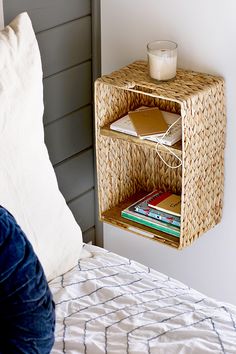 a wicker shelf with books on it next to a bed