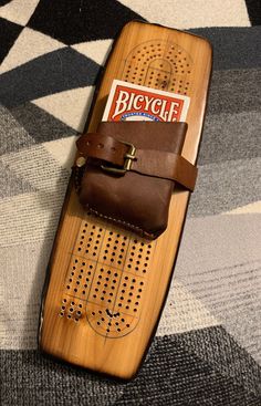 a wooden skateboard with a leather case on it's side and a magazine in its pocket