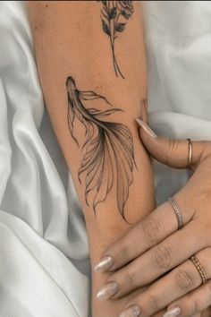 a woman's arm with a goldfish tattoo on it