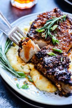 two pieces of meat on top of mashed potatoes and garnished with herbs