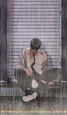 a man sitting on the ground in the rain