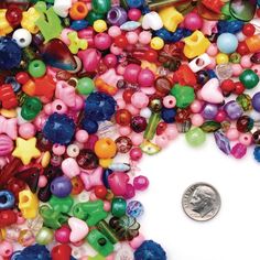 a pile of different colored beads next to a penny