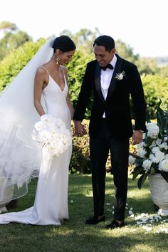 the bride and groom are holding hands in front of their wedding bouquets on the grass