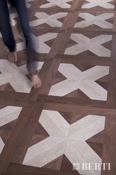 a person standing on top of a wooden floor next to a white and brown tile