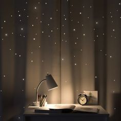 a desk with a lamp on it next to a window covered in stardusts