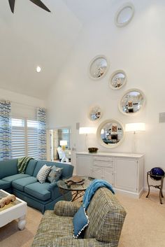 a living room filled with furniture and lots of mirrors on the wall above it's windows