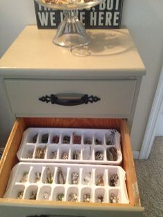 an open drawer in a white cabinet with jewelry inside it and a sign that says we are here