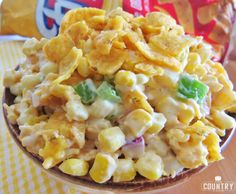 a bowl filled with corn salad next to a bag of chips