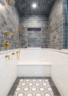 a bathroom with gray and white tiles on the walls, shower head, and bathtub