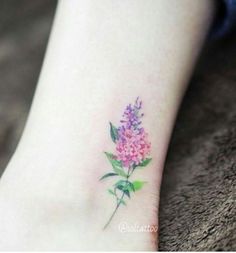 a small flower tattoo on the ankle is shown in pink and purple flowers, with green leaves