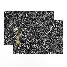 two black and white place mats with gold utensils in front of an intricately designed background