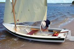 a small sailboat on the beach with a man standing in it's bow