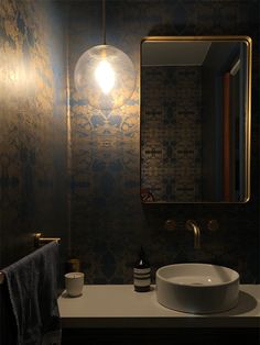 a bathroom sink under a mirror next to a wall mounted faucet with a light on it