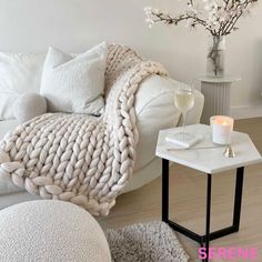 a living room with a white couch, coffee table and candles on the end tables