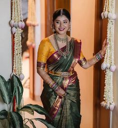 a woman in a yellow and green sari holding a potted plant with white flowers