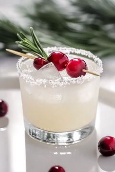 a drink with cranberries and rosemary garnish on the rim