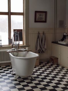 an old fashioned bathtub in a bathroom with black and white checkered flooring