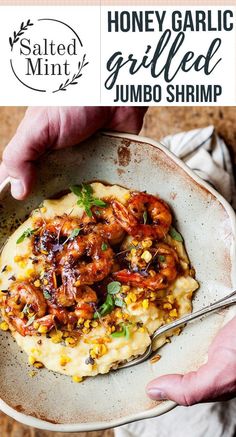 a bowl filled with shrimp and grits next to a hand holding a fork in it