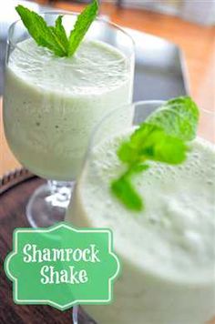 two glasses filled with green smoothies on top of a wooden table