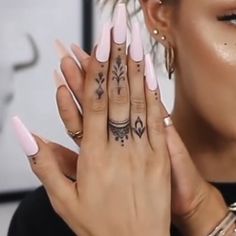 a woman holding her hands up to her face with tattoos on the fingers and hand