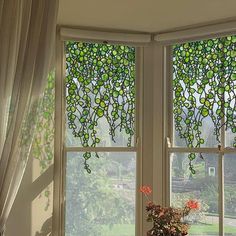 a vase with flowers sitting on top of a window sill next to two windows