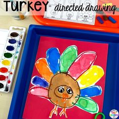 a turkey drawn on a piece of paper with watercolors and crayons next to it