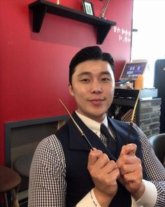 a man in a suit and tie is holding two knitting needles