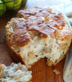 a loaf of bread sitting on top of a wooden cutting board next to some apples