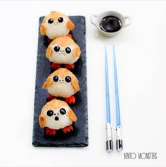 three small stuffed animals on a black plate next to chopsticks