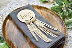 a wooden plate topped with a napkin covered in tassels and a tag on top of it